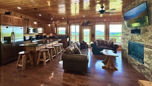 A spacious cabin interior with a kitchen, dining area, and a stone fireplace. - New Amazing View Cabin, 5 miles to Dollywood, 12 miles to Smokies, Sleeps 11 (Sevierville)