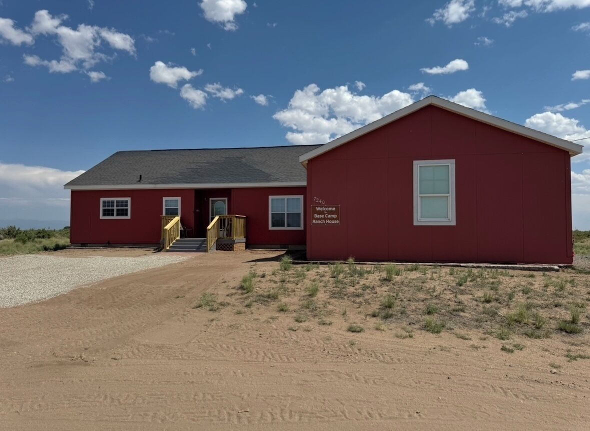 Een rood gebouw met een bord waarop staat: 'Welcome to Ranch House.'
