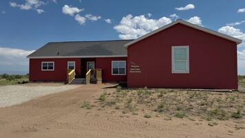 Een rood gebouw met een bord waarop staat: 'Welcome to Ranch House.'
