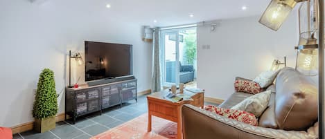 Una sala de estar moderna con televisor de pantalla plana, sofá de cuero y una mesa de centro.