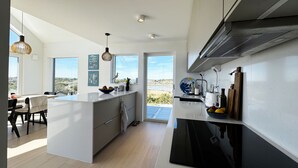 A modern kitchen with a central island, large windows, and a view of the landscape.