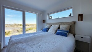 A bedroom with a large bed, a window, and a nightstand.