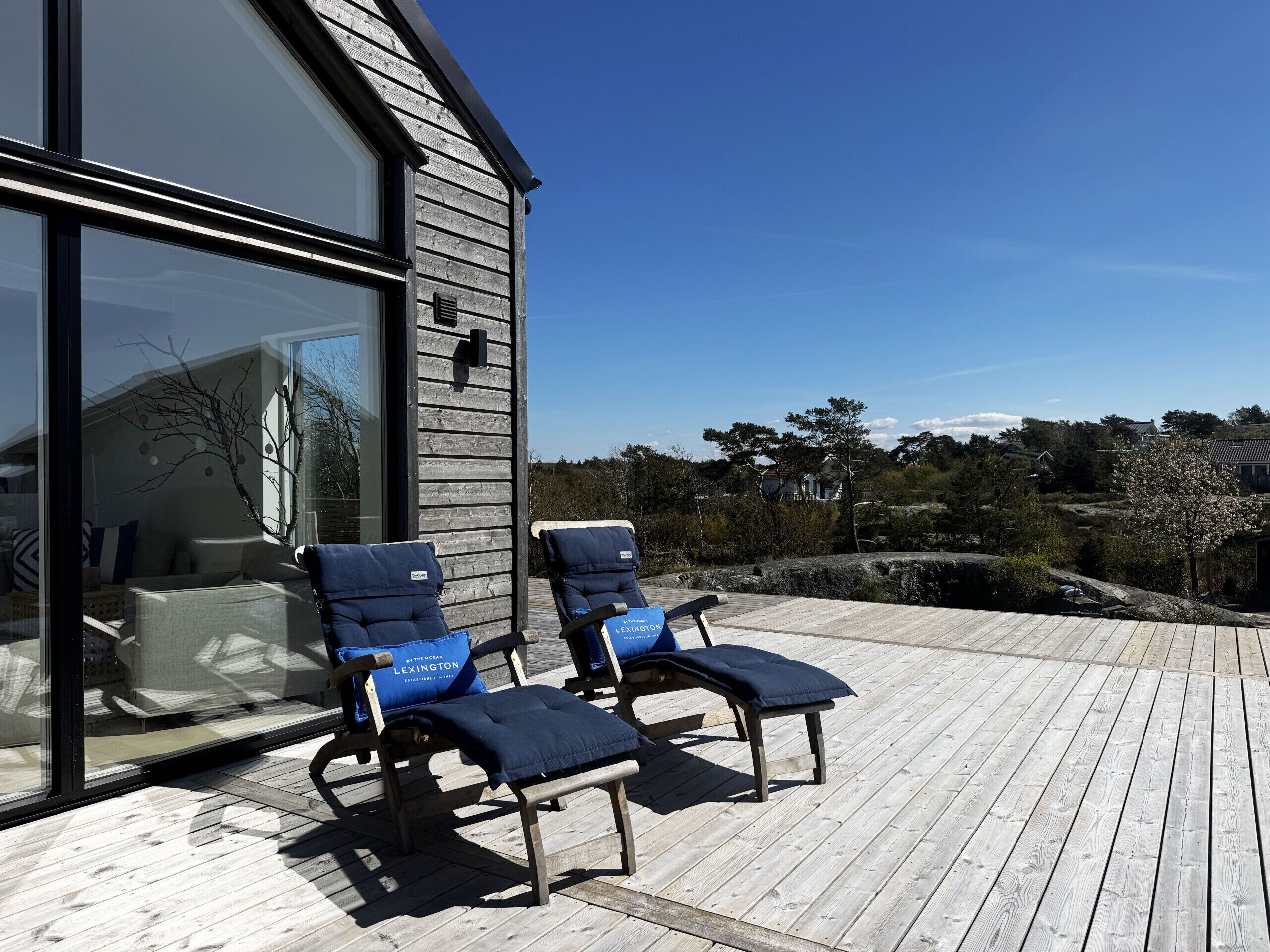 Una terraza con dos sillones de descanso y un muro de cristal de un edificio.