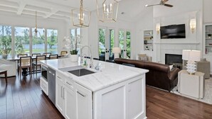 Una cocina amplia con una isla grande, un comedor con vistas y una sala de estar con chimenea.