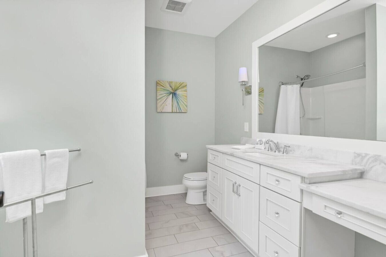 A modern bathroom with a white vanity, a large mirror, and a shower area.