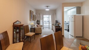 Un espacio habitable compacto con comedor, sofá, cocina y vistas a través de un ventanal.