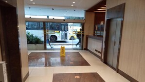 Un hall de hotel con suelo de baldosas, un mostrador de recepción y una puerta de cristal que da al exterior.