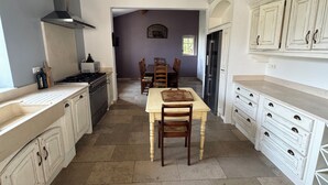 Una cocina con isla central, armarios blancos, estufa integrada y un amplio ventanal.