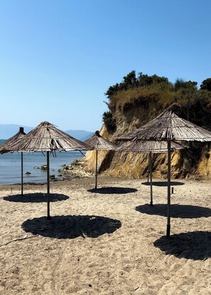 En privat strand, hvidt sand, liggestole, parasoller