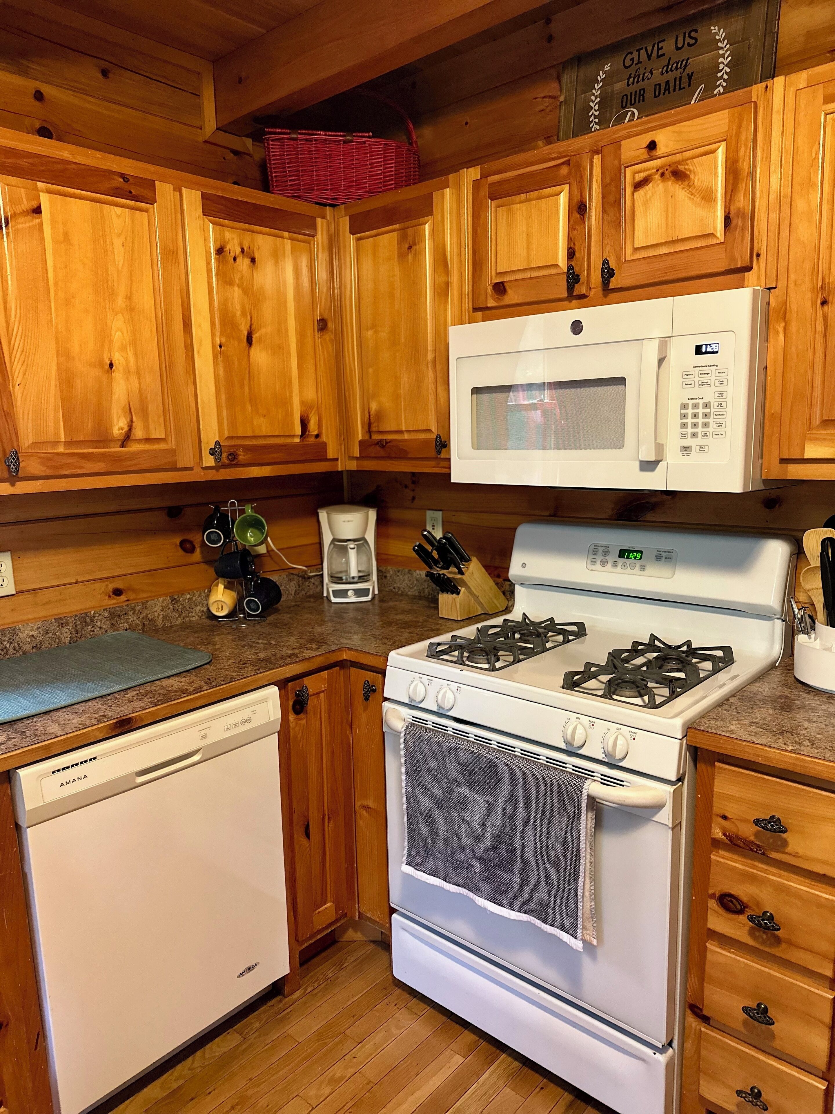A kitchen with wooden cabinets, a microwave, a stove, a dishwasher, and a coffee maker.
