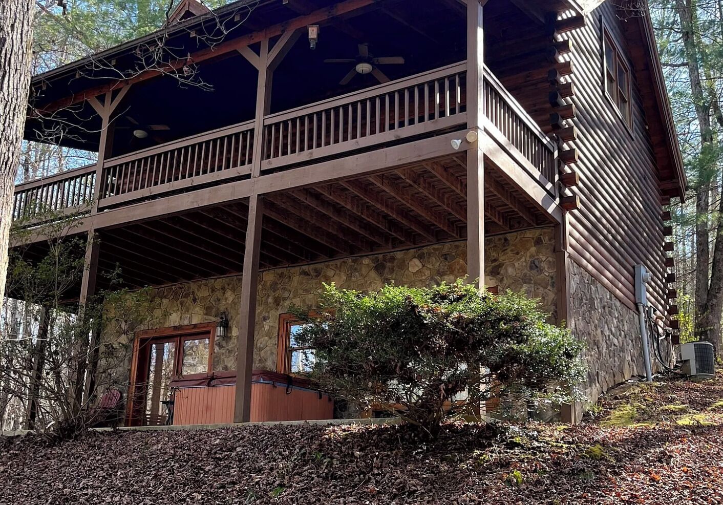 A wooden cabin with a stone facade, a balcony, and a small garden area.