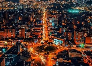 A nighttime aerial view of a densely populated urban area with illuminated buildings and streets. - Cold AC K Fast WiFi Medellin Paradise (Medellín)