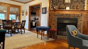 A cozy living room with a fireplace, wooden furniture, and a dining area with a table and chairs.
