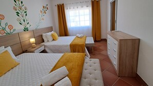 Una camera d'albergo con due letti, un comò di legno, uno specchio e una finestra con tende.