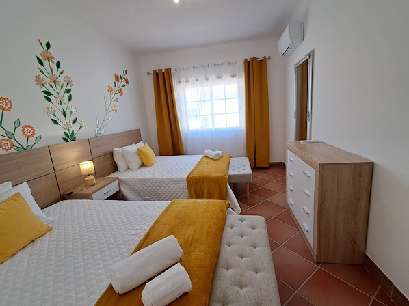 A hotel room with two beds, a wooden dresser, a mirror, and a window with curtains. - Villa Praia Porto e Mós (Lagos)