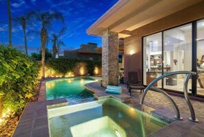 A swimming pool with a hot tub, surrounded by stone pillars and a glass-enclosed area with furniture. - Desert Dream Escape w/Pool (La Quinta)