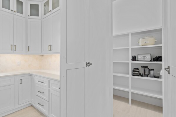 A modern kitchen with white cabinetry, a countertop, and a built-in oven. - The Sand Trap - Luxury Beach Getaway (Destin)