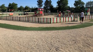Un espacio al aire libre cercado con suelo de arena, posiblemente un parque infantil o campo deportivo.