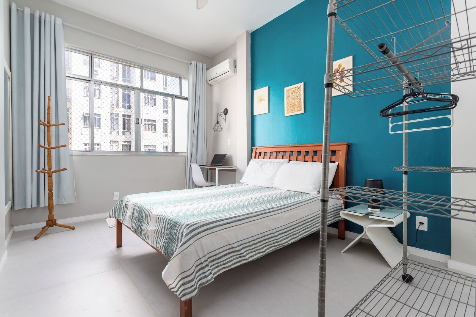 A modern bedroom with a bed, a desk, and a drying rack.