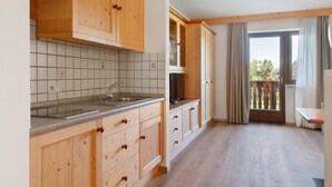 Una cocina con armarios de madera, salpicadero de azulejos y ventana que da a un balcón.