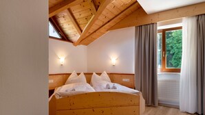 Ein Schlafzimmer mit einem hölzernen Bett, zwei Wandleuchten, einem Fenster mit Vorhängen und einem Oberlicht.