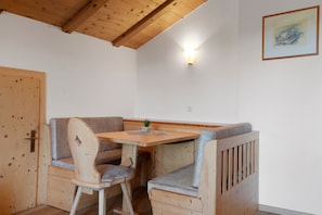 Un espacio con bancos de madera, una mesa, una puerta y una lámpara fijada a la pared.