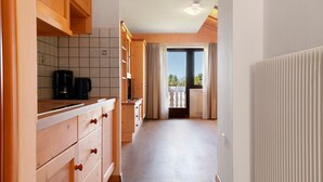 Eine Küche mit Holzschränken, einer Kaffeemaschine und Blick durch ein Fenster.