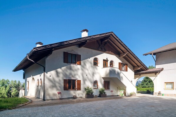 A two-story house with a sloped roof, wooden shutters, and a stone pathway leading to the entrance.