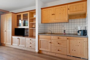 A kitchen with wooden cabinets, a tiled backsplash, and a coffee maker.