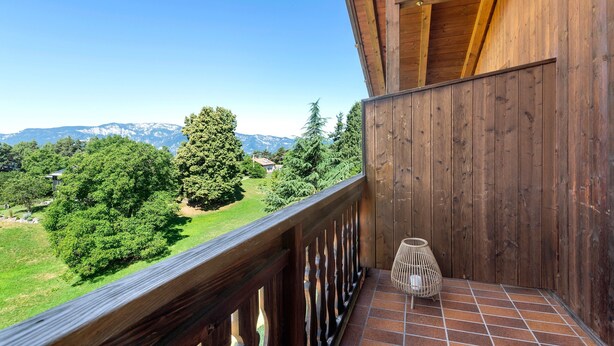 Un balcón de madera con vista a un paisaje verde y montañas.