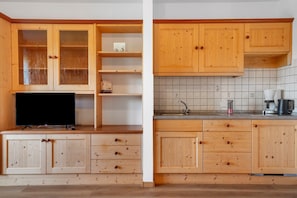 A kitchen with wooden cabinets, a countertop, a sink, and a coffee maker.