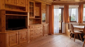 Una habitación con paneles de madera, un televisor, armarios y una zona de comedor.