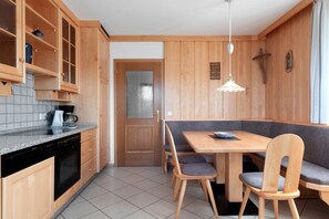 Une cuisine dotée de meubles en bois, d’un lave-vaisselle, d’une machine à café et d’un coin repas avec une table et des chaises.