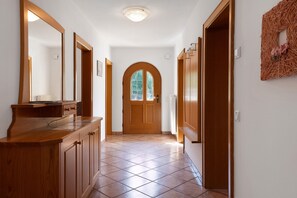 Un couloir avec une porte en bois, un miroir et un élément décoratif mural.