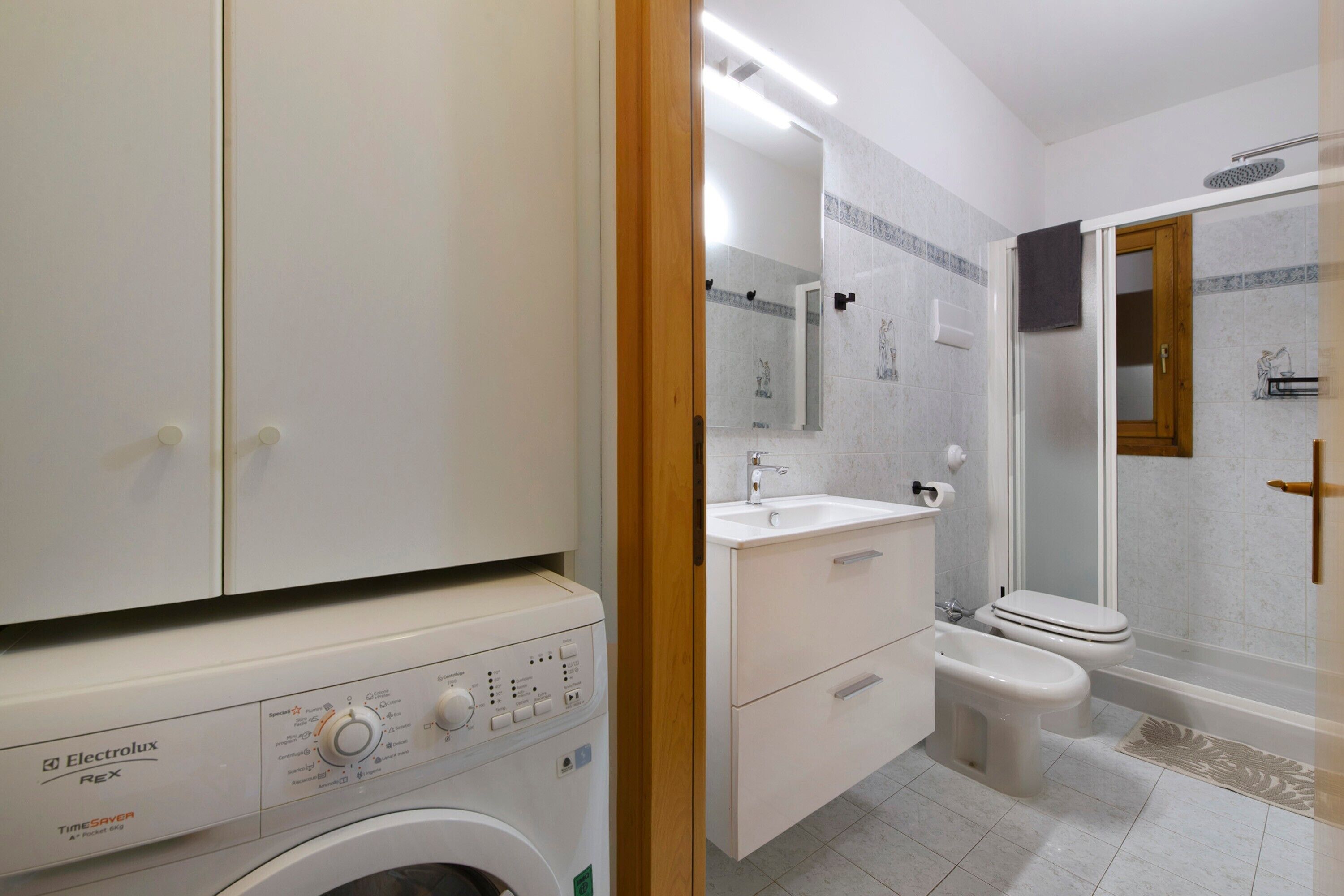 Une salle de bain moderne équipée d’un lave-linge, d’un évier, de toilettes et d’une douche.
