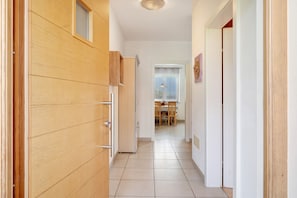 A hallway leading to a dining area with a window, wooden cabinets, and a tiled floor. - Apartment 'Pink Lady' with Mountain View, Shared Terrace and Wi-Fi (Appiano sulla Strada del Vino)