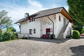 A white building with a tiled roof, a staircase, and a bench outside. - Apartment 'Pink Lady' with Mountain View, Shared Terrace and Wi-Fi (Appiano sulla Strada del Vino)