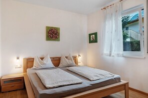 Una camera da letto con un letto, comodini, una finestra con tende e opere d'arte appese al muro.
