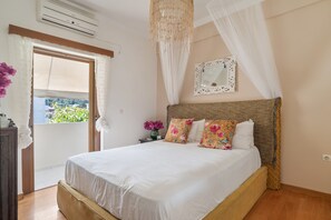A bedroom with a large bed, a bedside table, a nightstand, a mirror, and a window with curtains. - Apartment 'Theodoros  1' with Sea View, Wi-Fi and Air Conditioning (Nikiana)