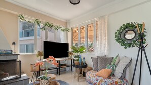 A living room with a fireplace, a TV, a sofa with cushions, and a decorative mirror. - Apartment 'Theodoros  1' with Sea View, Wi-Fi and Air Conditioning (Nikiana)
