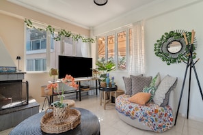 A living room with a fireplace, a TV, a sofa with cushions, and a decorative mirror. - Apartment 'Theodoros  1' with Sea View, Wi-Fi and Air Conditioning (Nikiana)