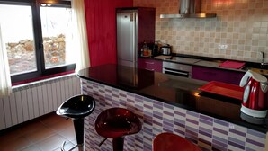 A kitchen with a refrigerator, stove, and bar stools.