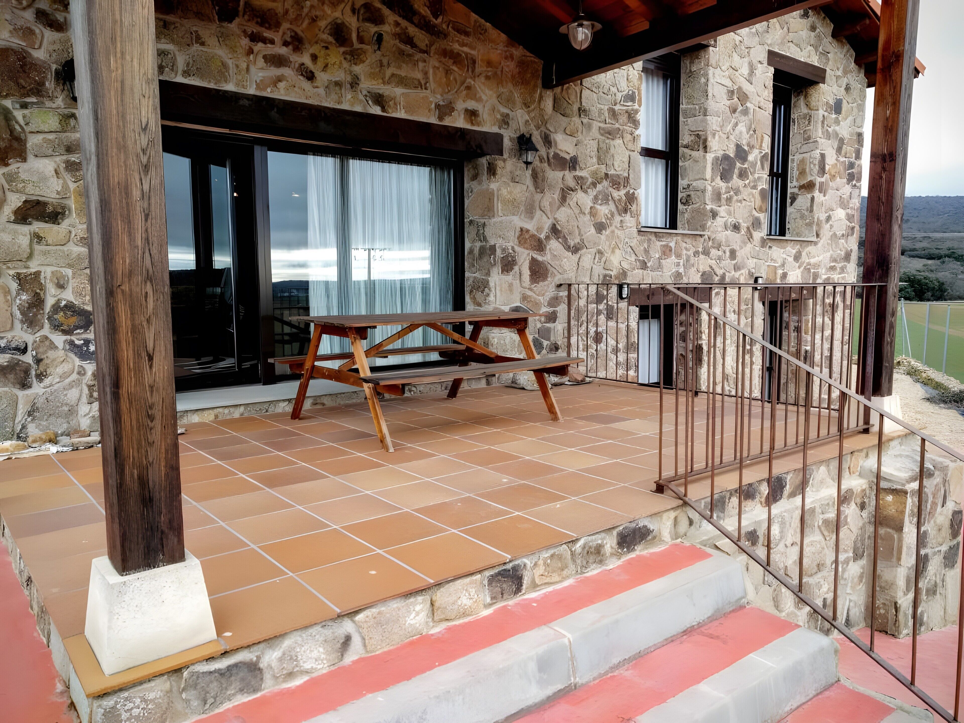 Un edificio in pietra con un tavolo di legno e scale che conducono a un balcone.