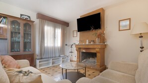 Ein Wohnzimmer mit Kamin, Sofa, Sessel und einem Glastisch.
