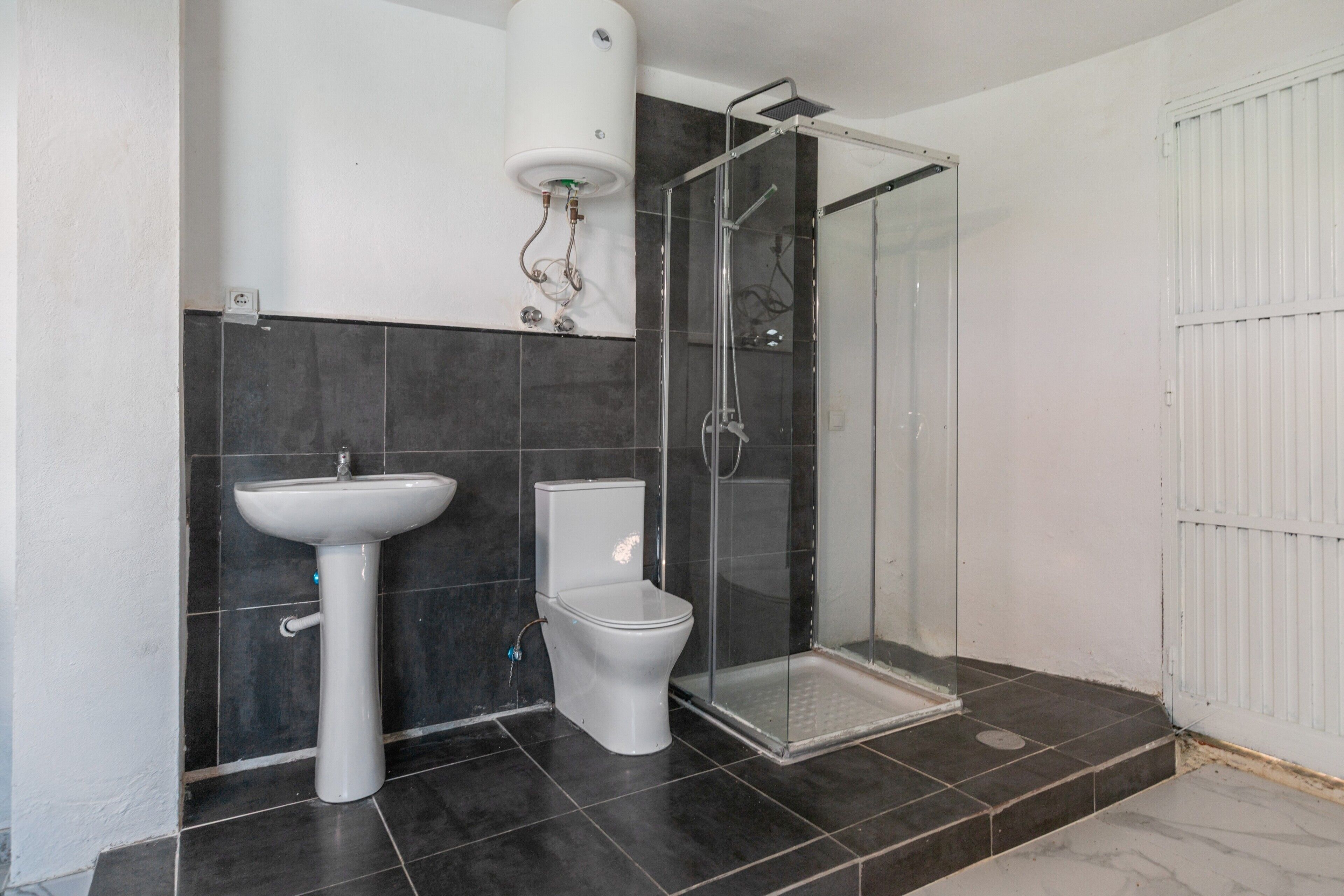 A bathroom with a pedestal sink, toilet, and a glass-enclosed shower.
