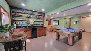 Una mesa de billar en una habitación que tiene una zona de cocina, una mesa de comedor y un sofá.