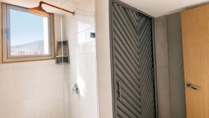 Um banheiro moderno com box de vidro, porta de madeira e vista para a cidade.