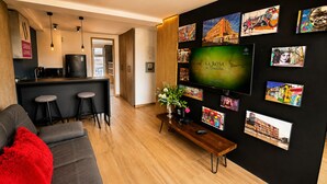 Uma sala de estar moderna com televisão, espaço de bar e obras de arte nas paredes.