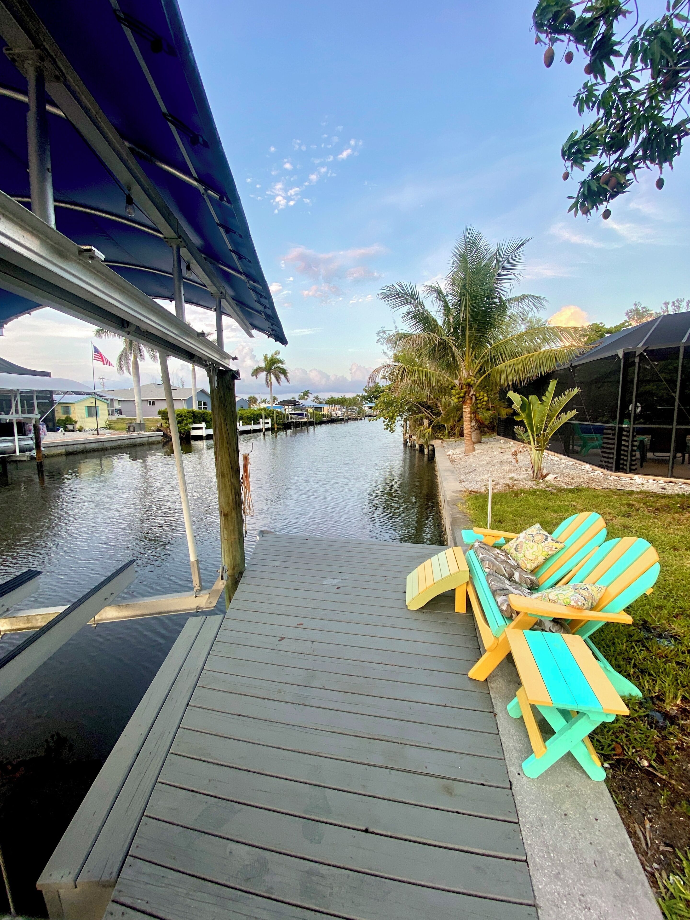A dock with a covered seating area and a view of a calm waterway with boats.