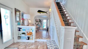 A spacious hallway with a tiled floor, a wooden bench, a staircase with patterned carpet, and a fish decoration on the wall. - Paradise Point in St James City  (Saint James City)